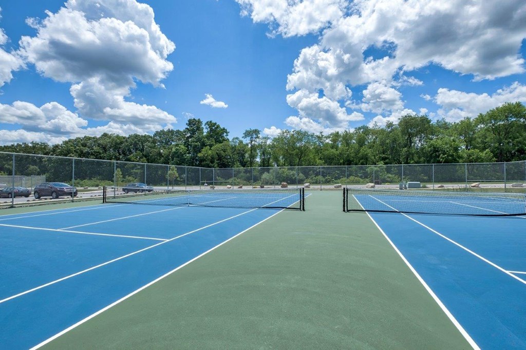 a tennis court with blue and green courts and a fence
