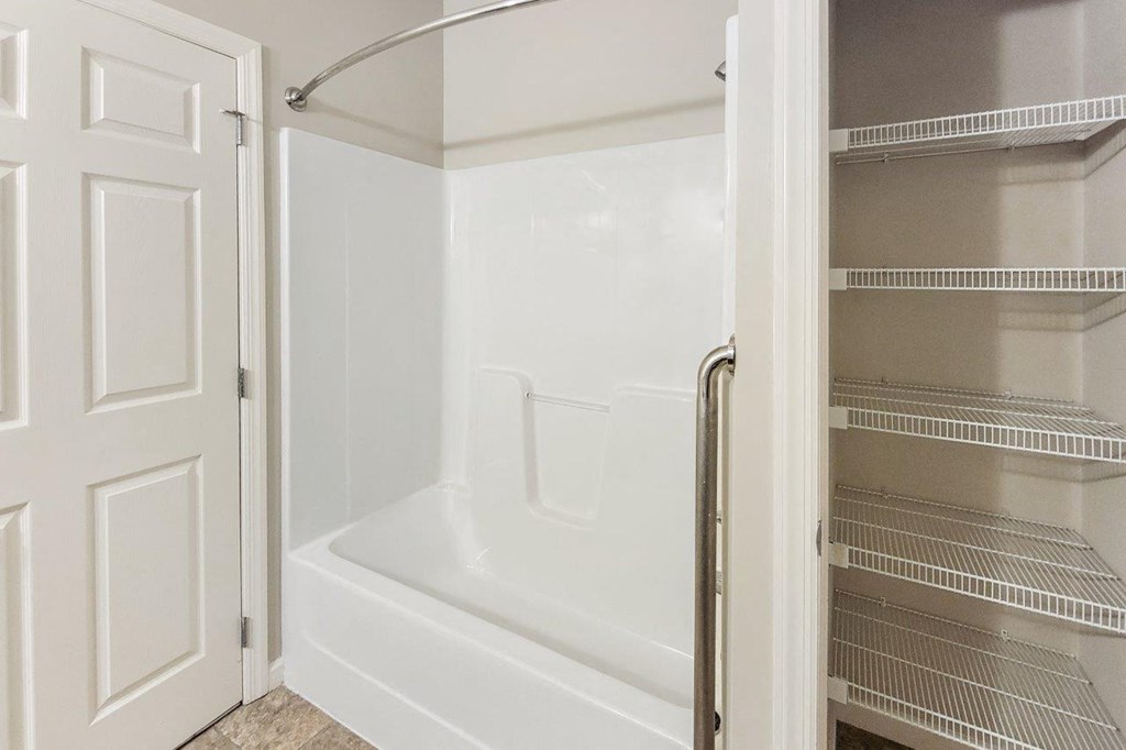 the walk in shower in the master bathroom of a home with an open door