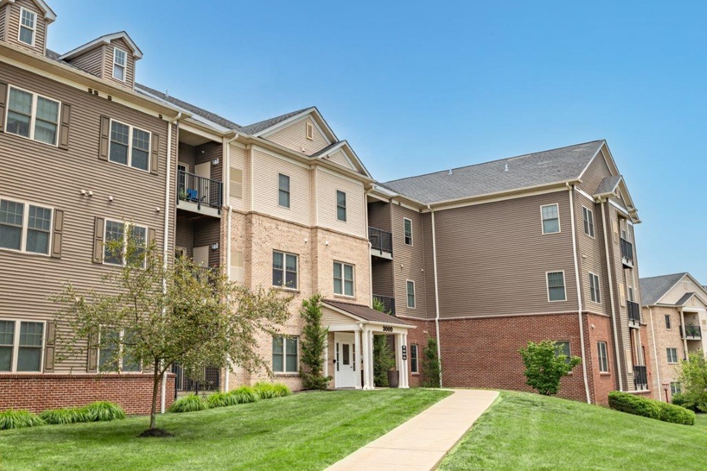 a sidewalk leading to an apartment building with grass