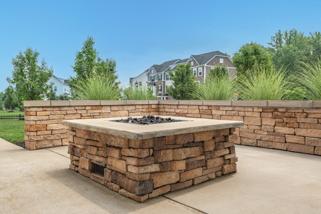 a fire pit with a stone wall in front of a house
