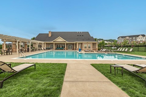 a swimming pool with lounge chairs and a house in the background