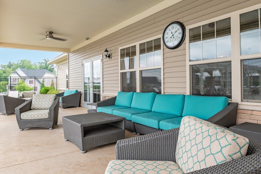 a covered porch with couches and chairs and a clock on the wall
