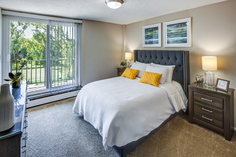 A bedroom with a large bed and a window overlooking a green area.