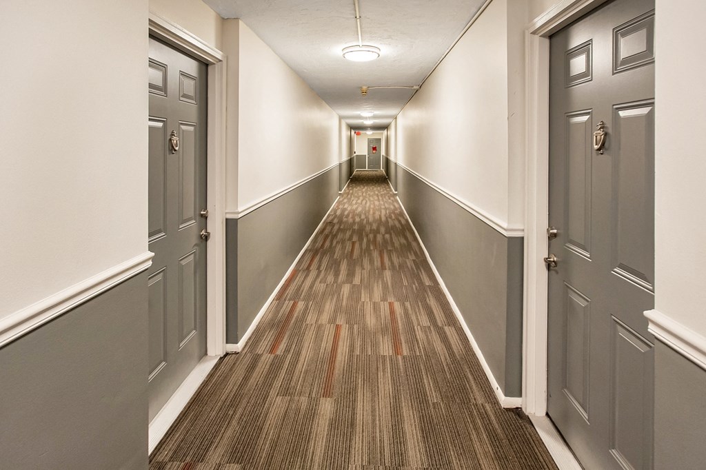 a hallway with gray doors and a wooden floor and white walls