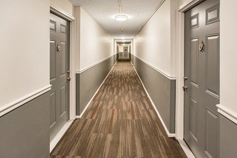 a hallway with gray doors and a wooden floor and white walls