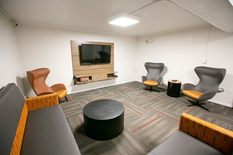 a living room with chairs and a television