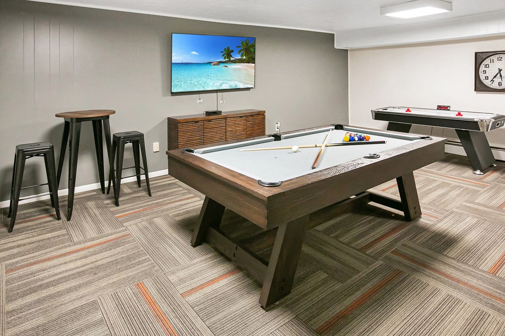 a games room with two pool tables and a tv in a community room