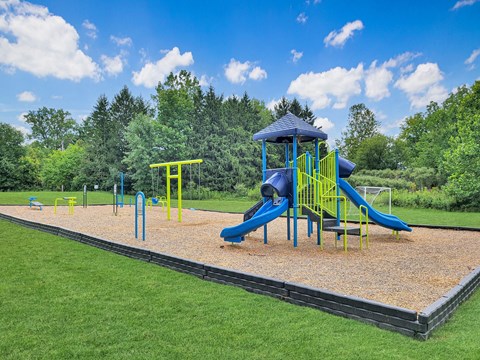 a playground with a blue slide and yellow playset in a park