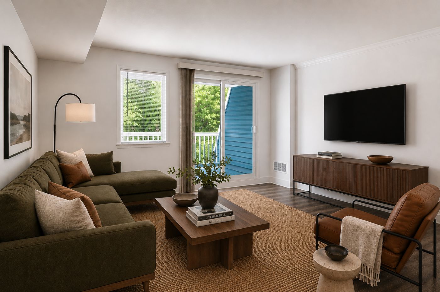 A living room with a green couch, a brown armchair, a wooden coffee table, and a flat-screen TV mounted on the wall.