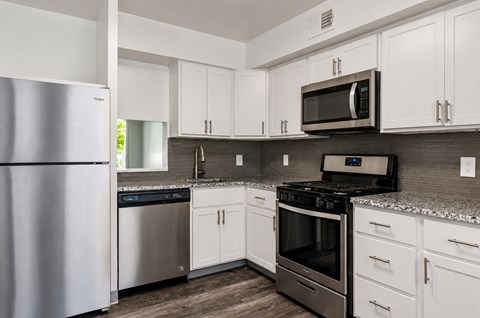 A kitchen with white cabinets and a black microwave above the stove.