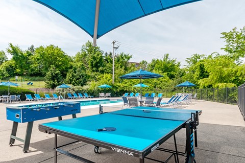 two ping pong tables with chairs and umbrellas at the enclave at legends