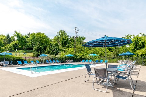 a swimming pool with blue umbrellas and chairs next to it