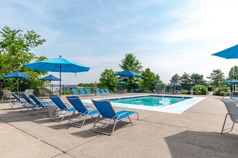 a swimming pool with blue chairs and umbrellas next to it