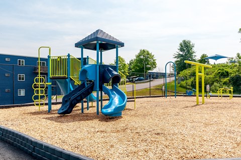 a playground with a blue slide and a yellow structure
