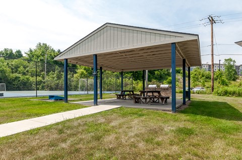 a pavilion with a picnic table next to a tennis court