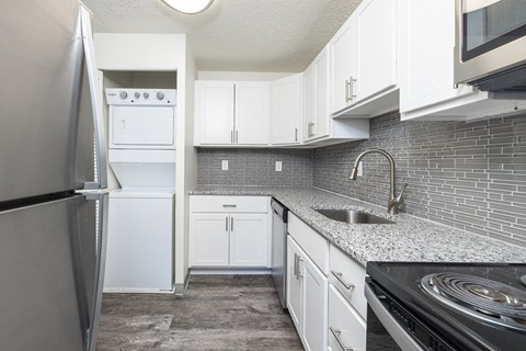an empty kitchen with white cabinets and stainless steel appliances