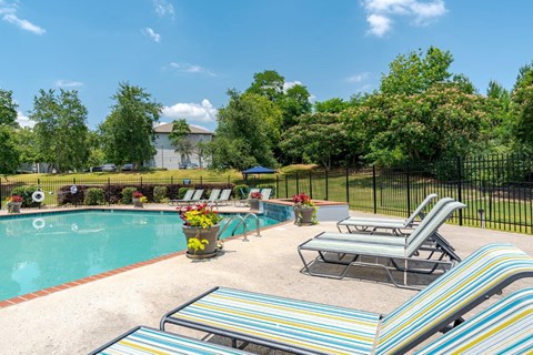 a swimming pool with chairs and a poolside table