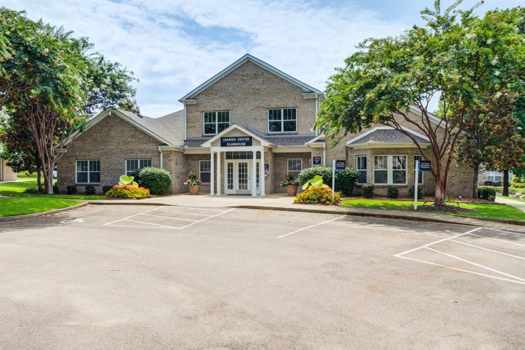 an empty parking lot in front of a brick house