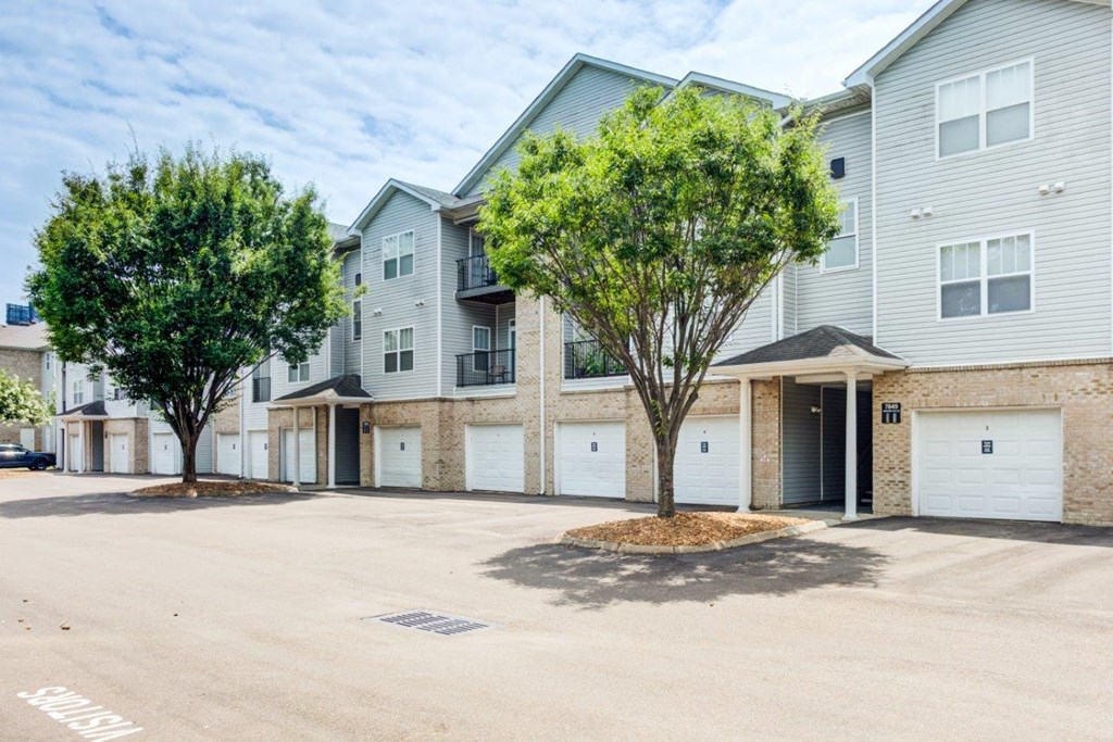 an empty parking lot in front of two buildings with trees
