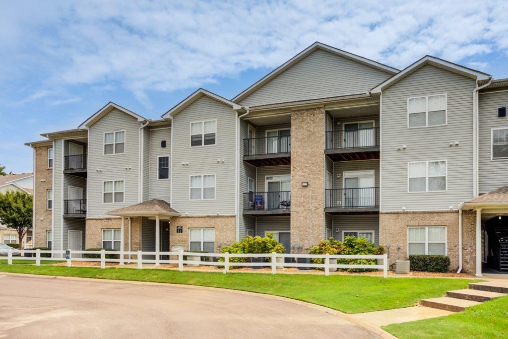 the outlook of an apartment building with a driveway and grass
