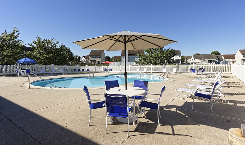 an umbrella over a table and chairs next to a swimming pool