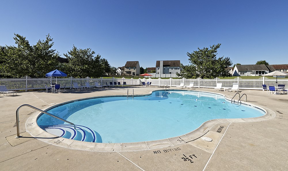 an empty pool at a resort with houses in the background