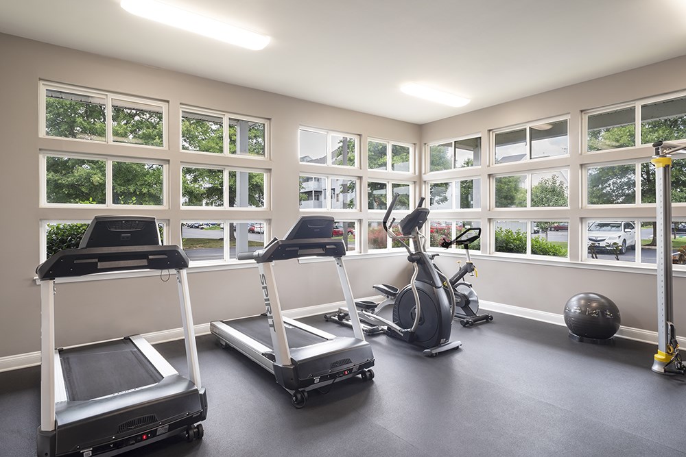 a gym with treadmills and other exercise equipment and windows