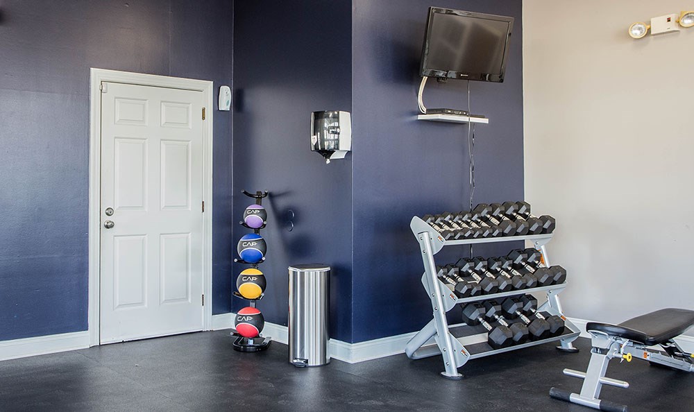 a fitness room with weights and a chair and a tv