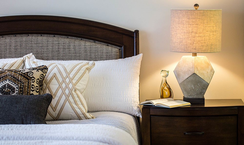 a bedroom with a bed and a night stand with a lamp