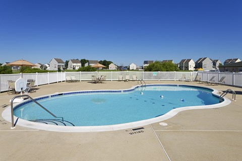 a resort style pool with chairs and a fence around it