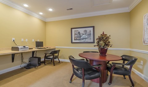 a business center with a table and chairs and a computer