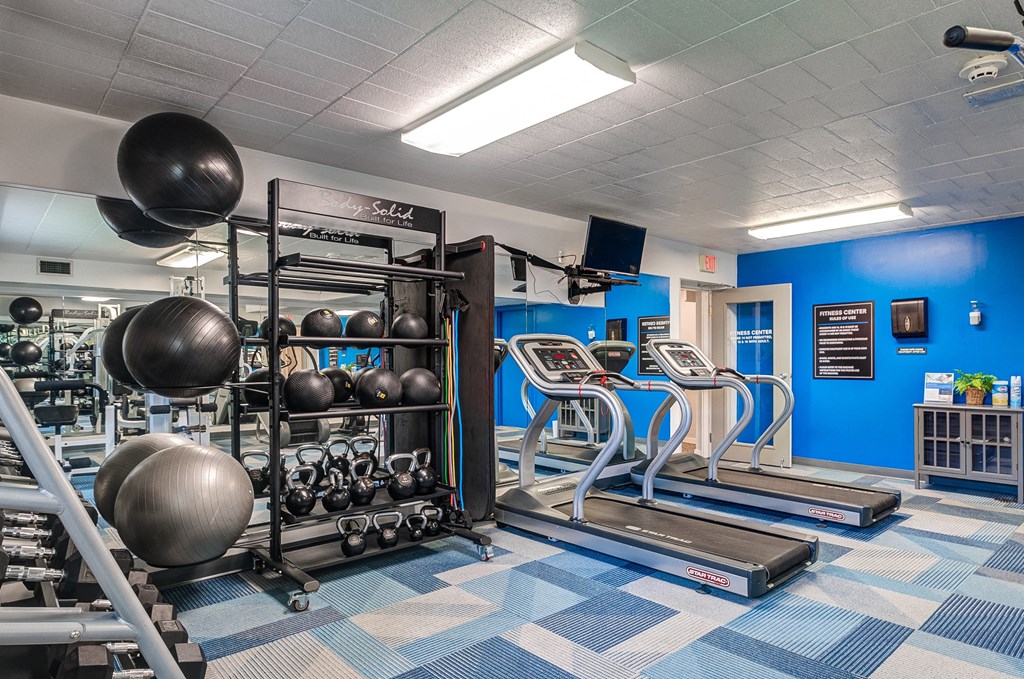 a gym with weights and cardio equipment in a building with blue walls