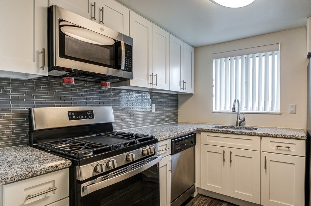 an updated kitchen with granite counter tops and stainless steel appliances