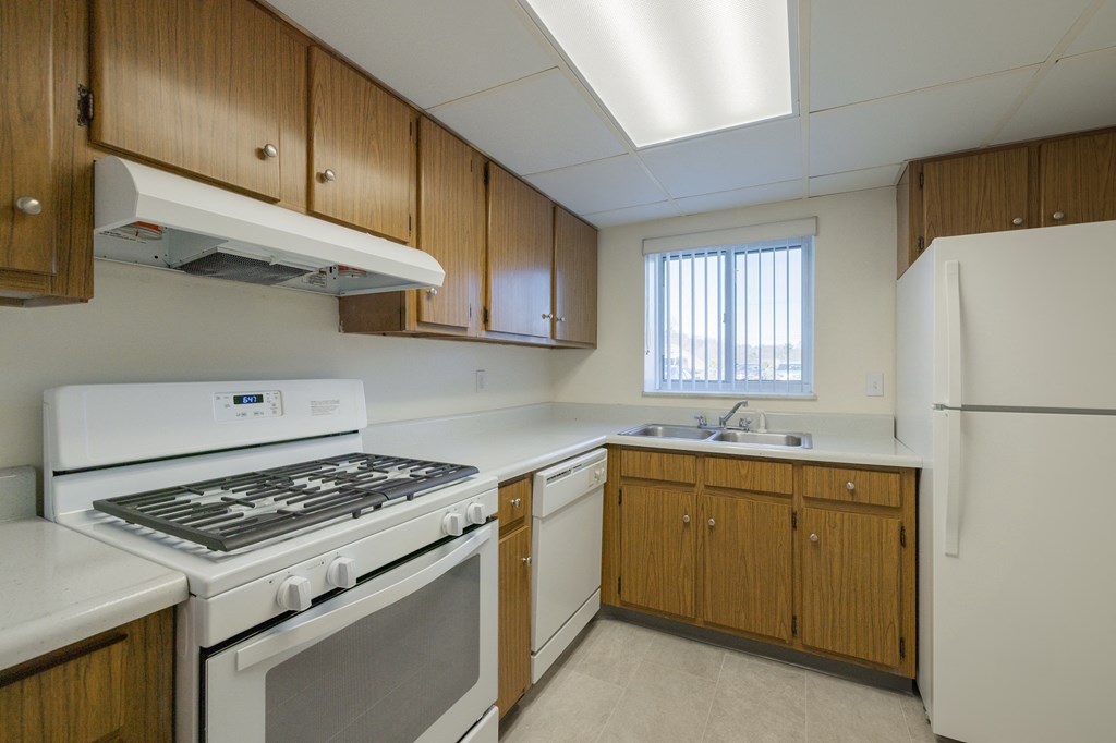 an empty kitchen with white appliances and wooden cabinets