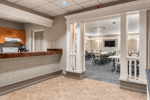 A room with a bar area and a dining area with chairs and tables.