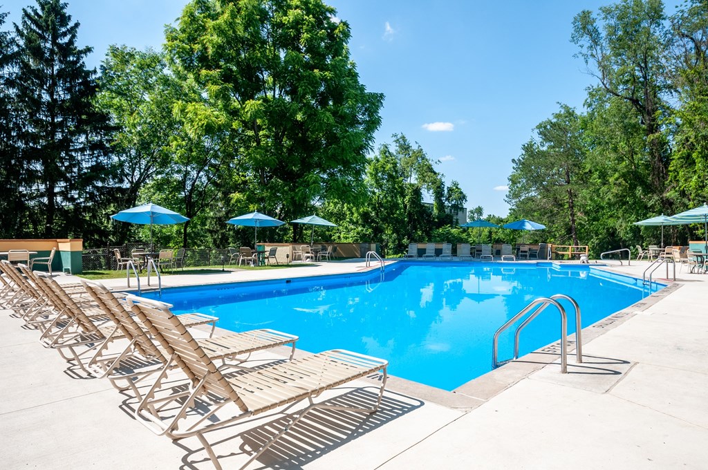 a swimming pool with wooden chairs and umbrellas