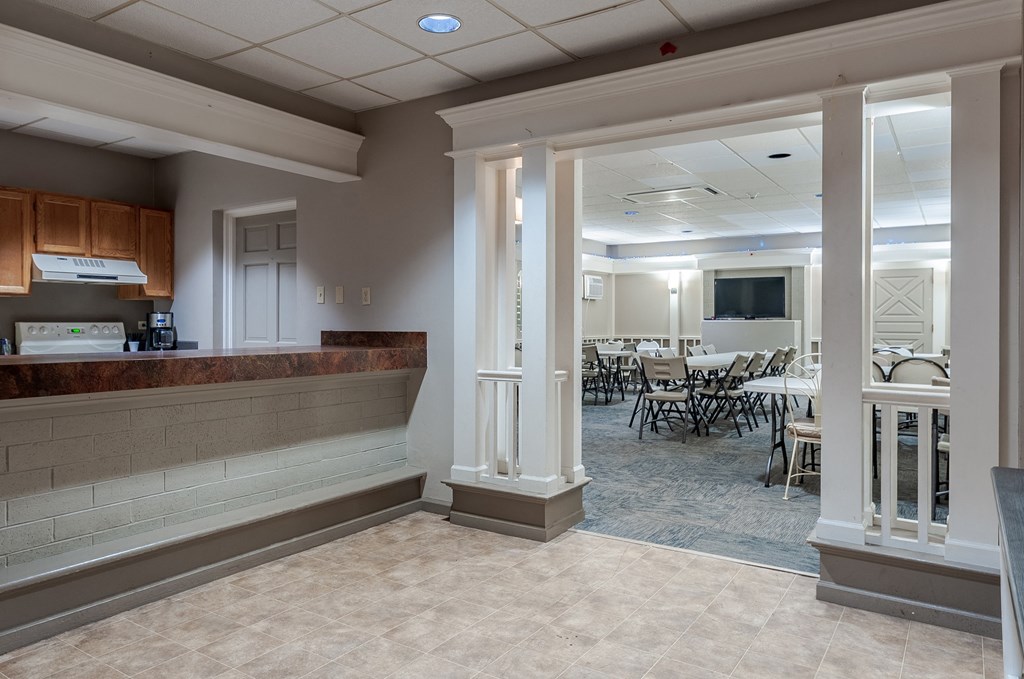 a lobby with pillars and a counter and a dining room with tables and chairs