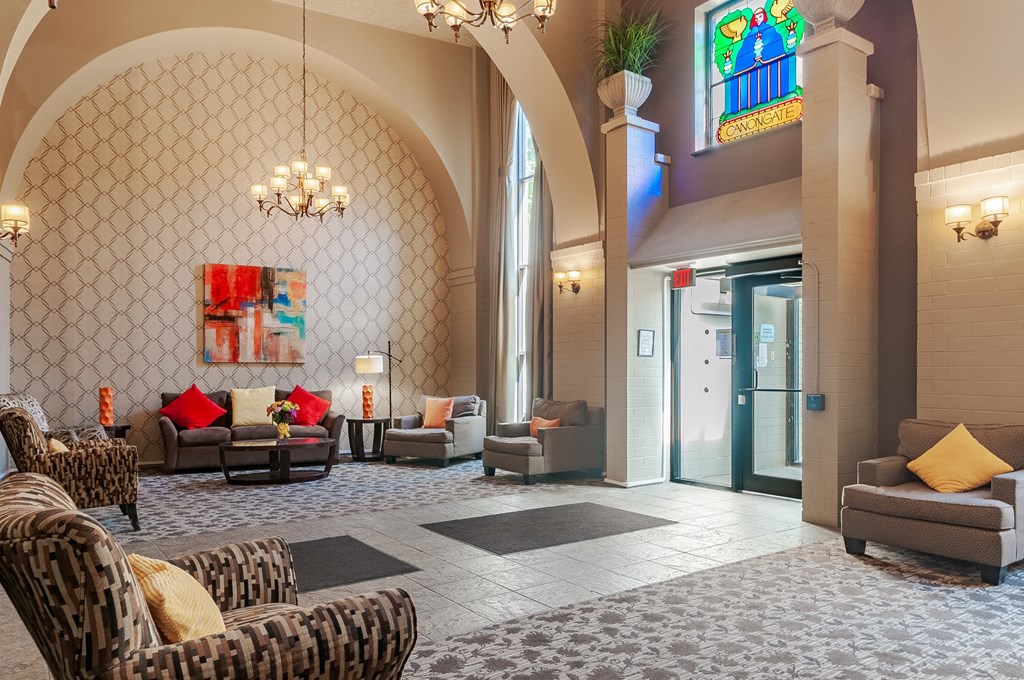 a lobby with couches and chairs and a stained glass window