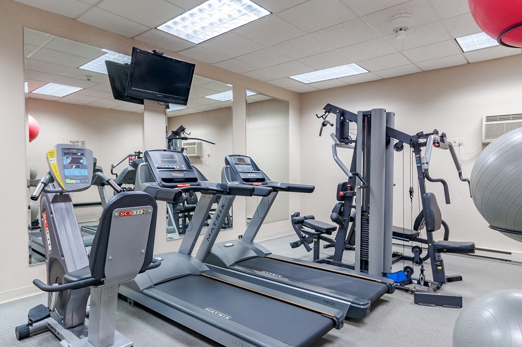 a gym with various exercise equipment and a tv