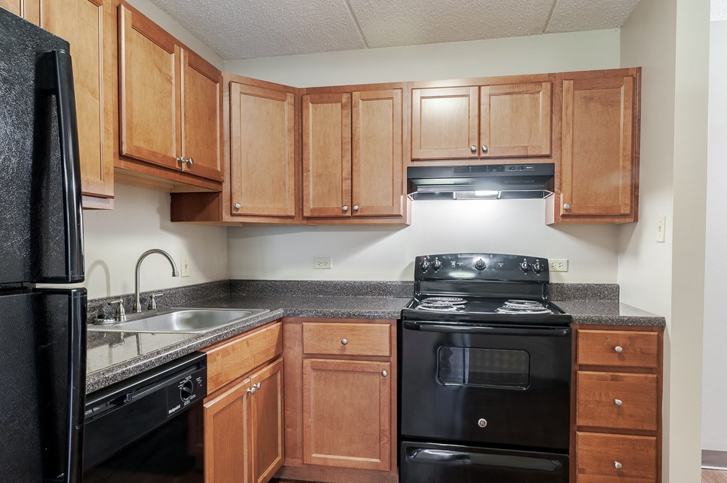 an empty kitchen with black appliances and wooden cabinets