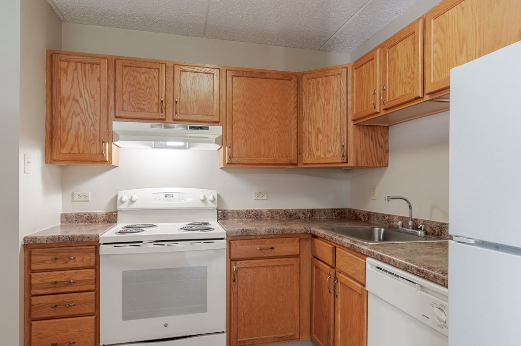 an empty kitchen with white appliances and wooden cabinets