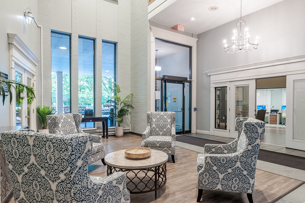 a lobby with chairs and a table and windows