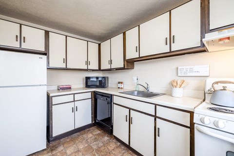 A kitchen with white cabinets and a white fridge.