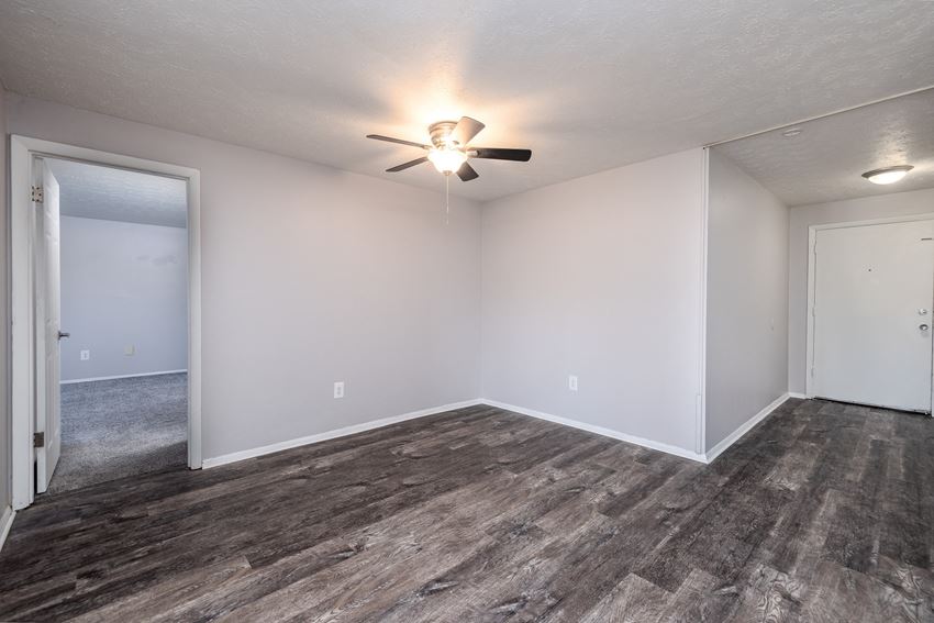 an empty living room with wood flooring and a ceiling fan