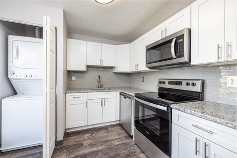 A kitchen with white cabinets and a black microwave above the stove.