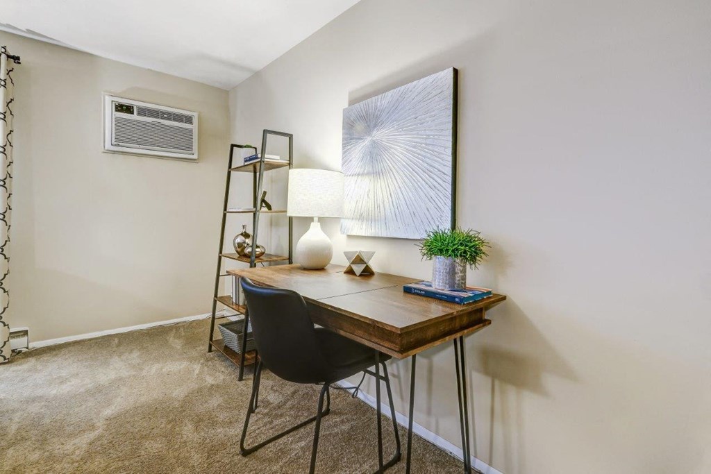 an office with a desk and a window with an air conditioner