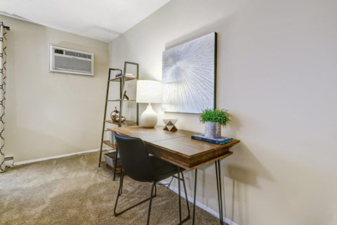 A room with a desk, chair, and a painting on the wall.