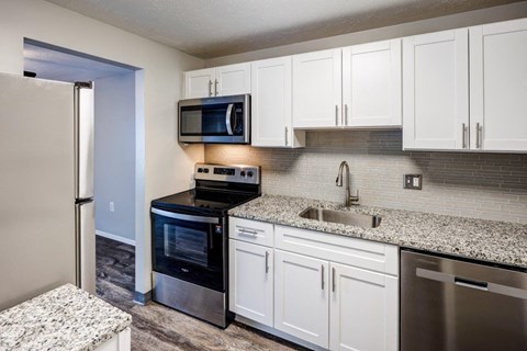A kitchen with white cabinets and a granite countertop.