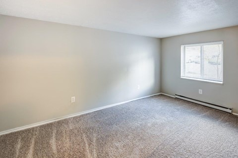 A room with a window and carpeted floor.