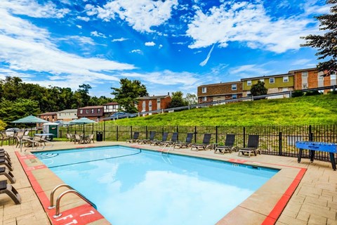 A swimming pool surrounded by lounge chairs and trees.